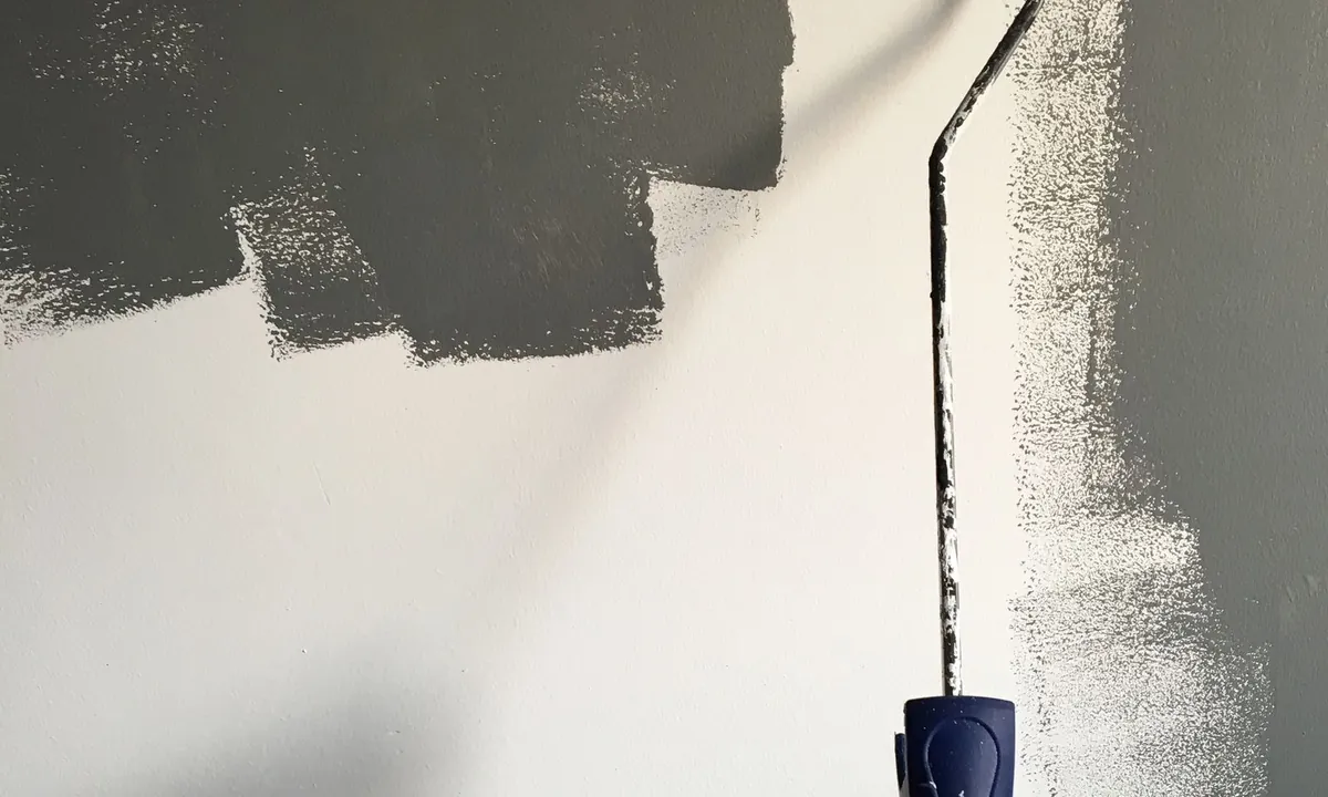 Application d’une peinture grise au rouleau sur un mur intérieur